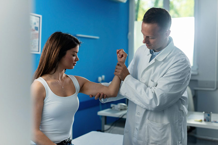 young-woman-getting-her-arm-elbow-examined-by-male-orthopedist-medical-appointment-clinic-Well-Woman-Annual-Physical-Exam Well Woman Annual Physical Exam